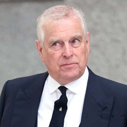 Prince Andrew wears a black suit and matching tie with a white shirt and looks to the sky in a bemused quizzical way