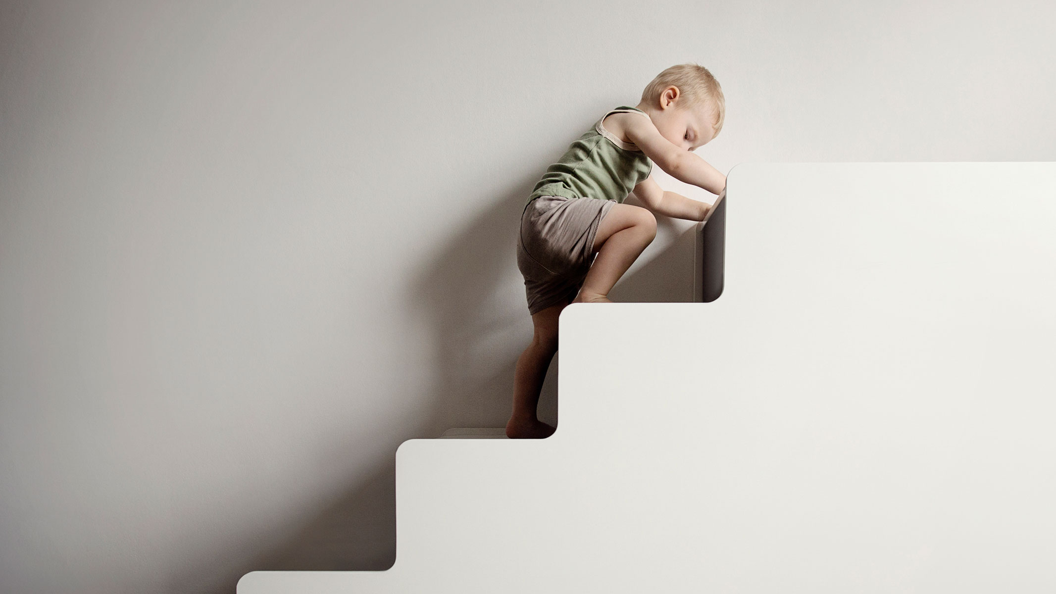 A picture of a toddler boy climbing up the stairs