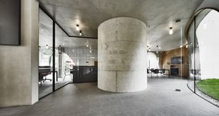 Open space in office with concrete pillar, concrete ceiling and view out to grass area