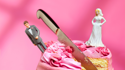 Knife cutting cake between bride and groom figurines
