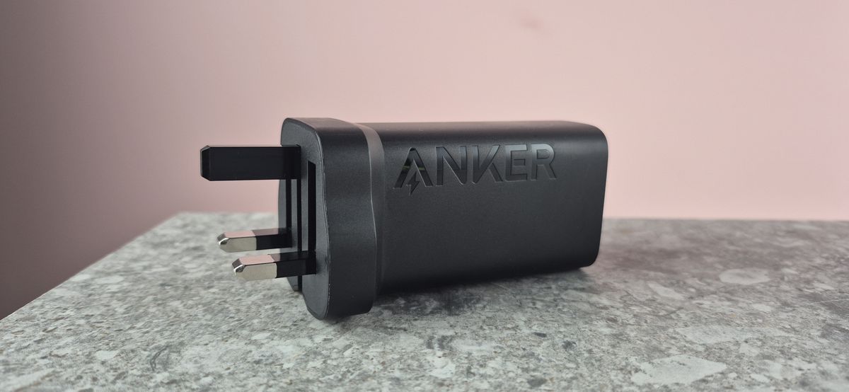 Anker 335 Charger (67W) on stone surface against pink background