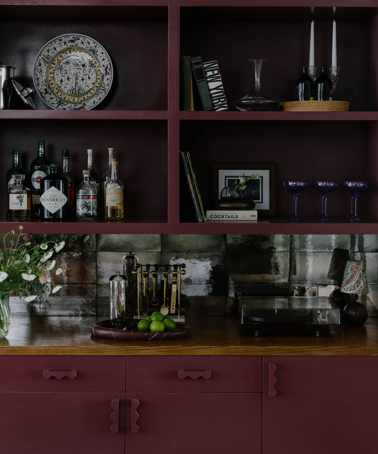 A maroon home bar with shelving and funky hardware