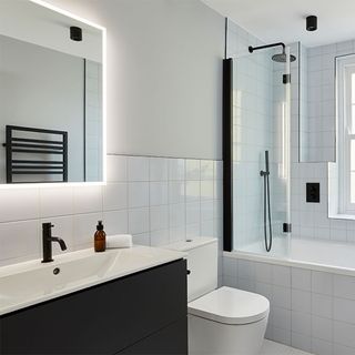 white tiled bathroom with bathtub washbasin and commode