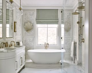 An example of ensuite ideas showing a white free-standing bath in front of a window in a grand bathroom