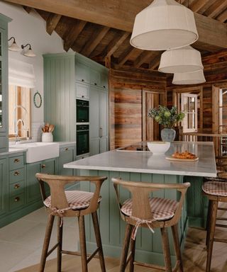 Shaker kitchen, green shaker kitchen in chalet, marble countertops, large cream pendant lights, wood bar stools