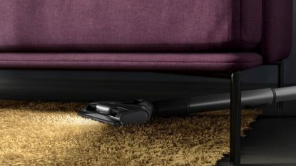 AEG 8000 vacuum cleaning underneath purple sofa on yellow rug