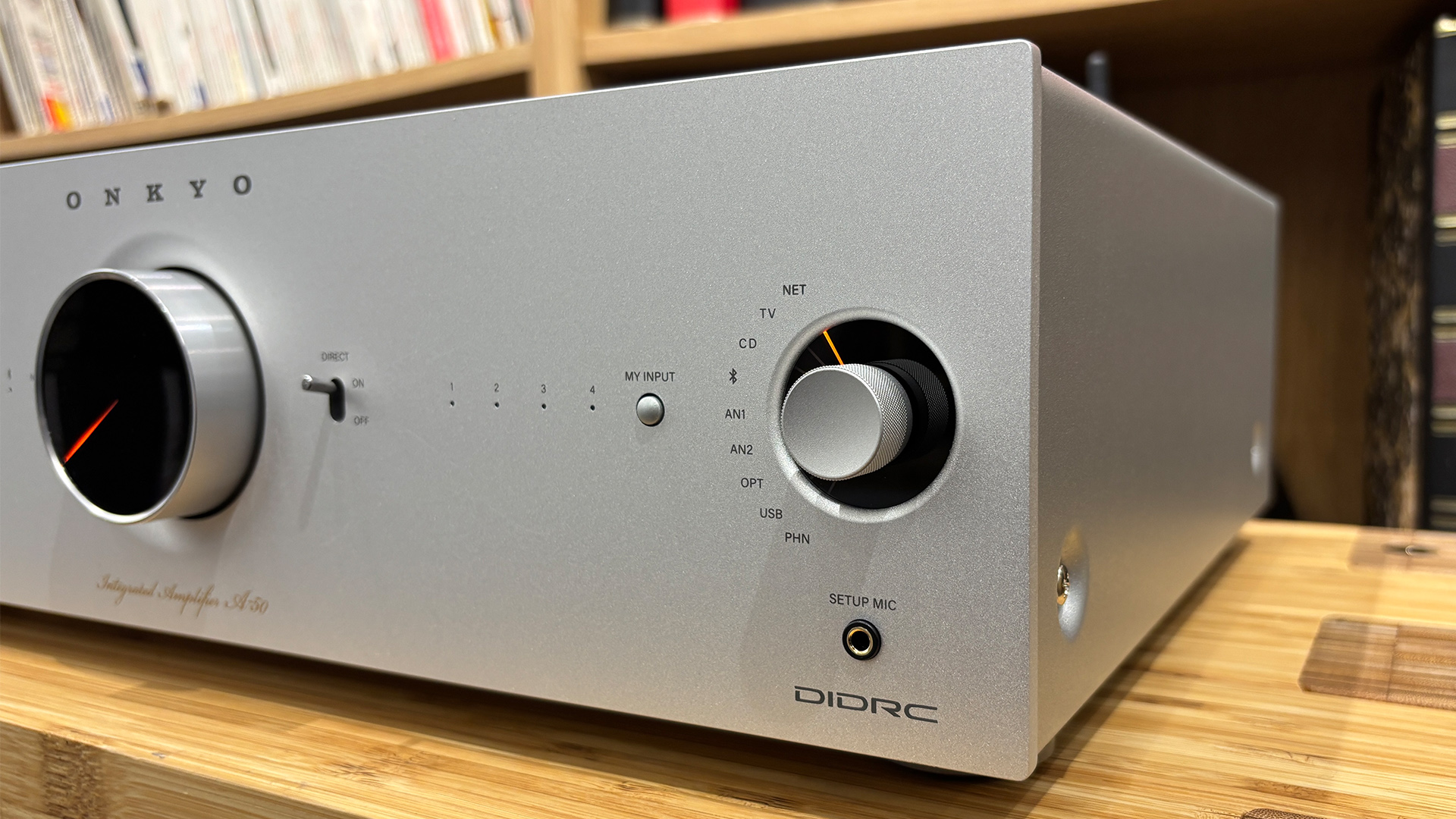 Onkyo Icon A-50 streaming amplifier on wooden hi-fi rack in front of bookcase detail of dials
