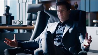 Jonathan Groff gestures widely while sitting in a chair in The Matrix Resurrections.