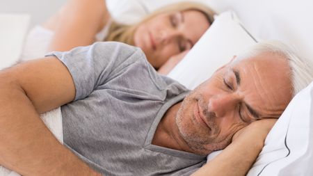 An older couple sleep peacefully.