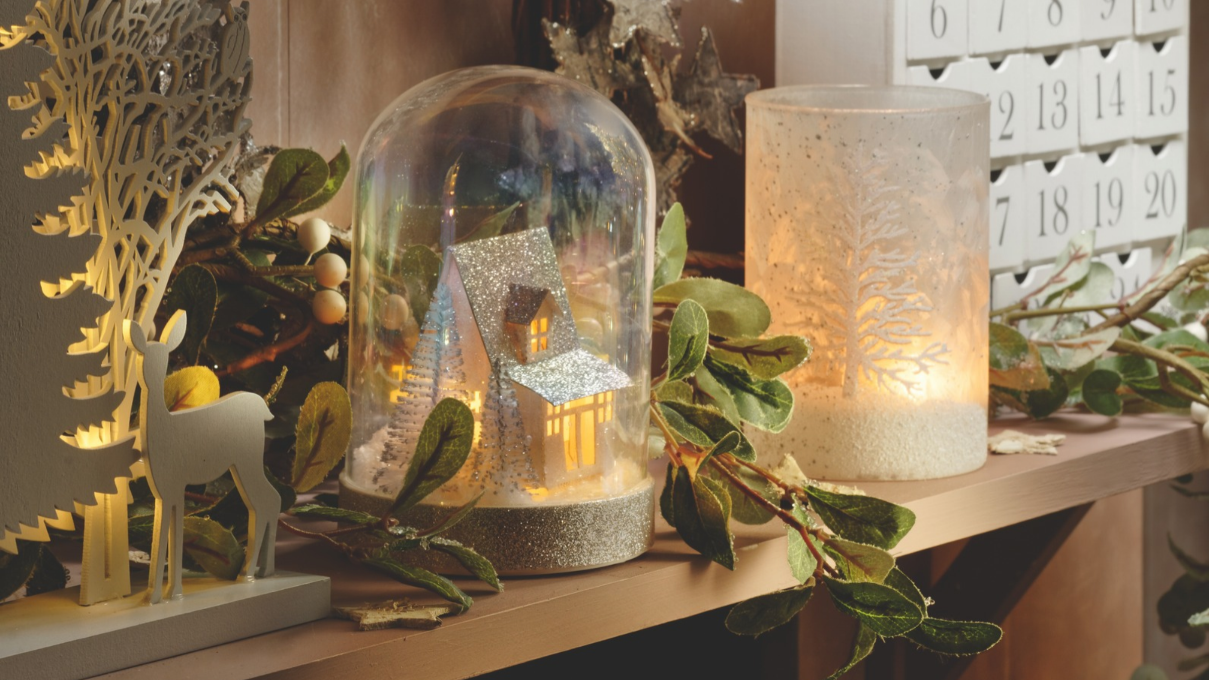 Detail of Christmas decorations, advent calendar, lit candles and ornaments on mantelpiece.
