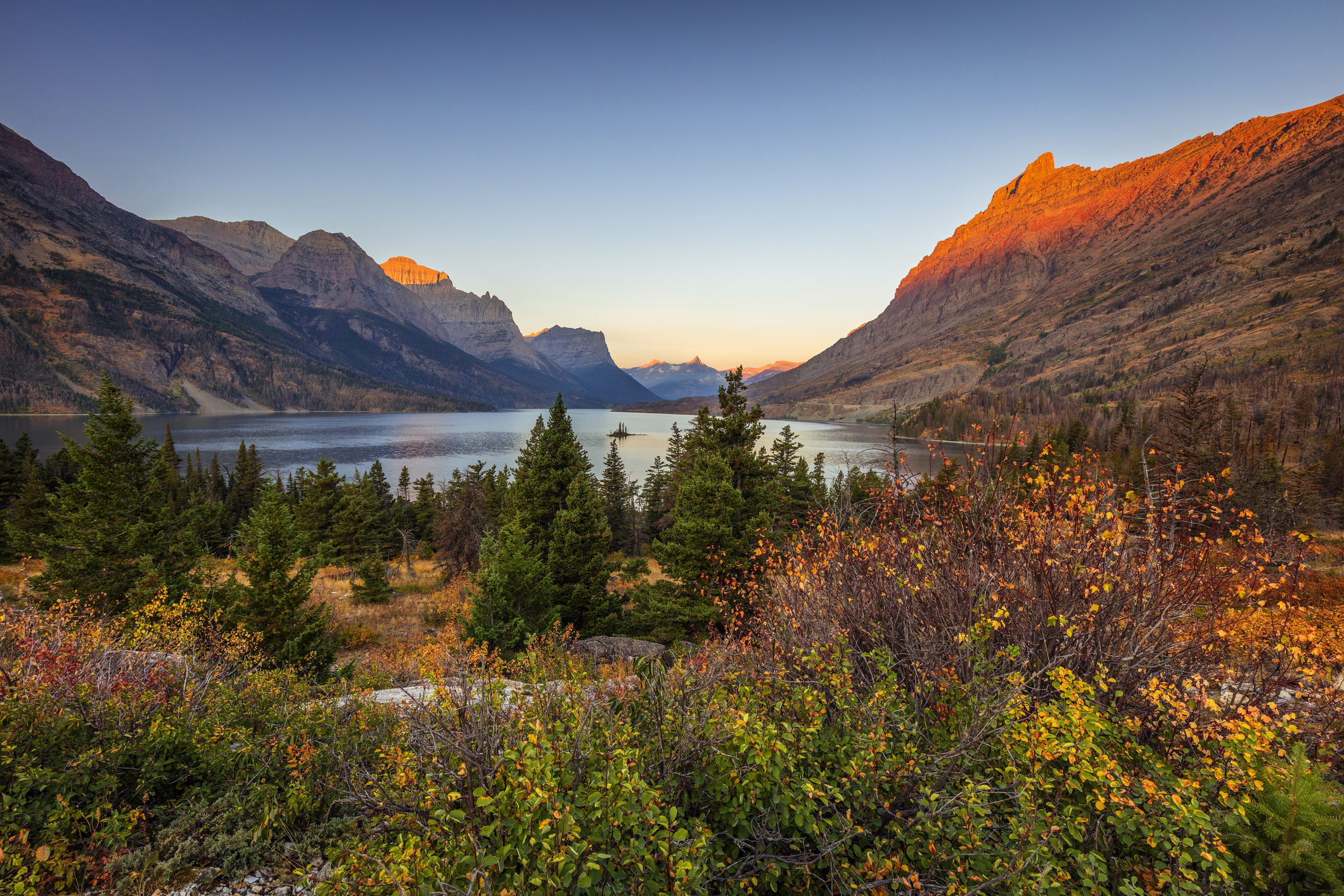 A digital photo of an autumn sunrise over the mountains that tower over Saint Mary Lake in Glacier National Park.