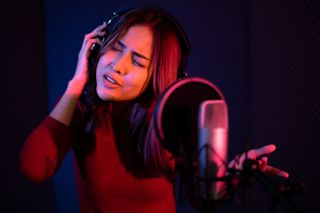 Women wearing headphones sings into a microphone