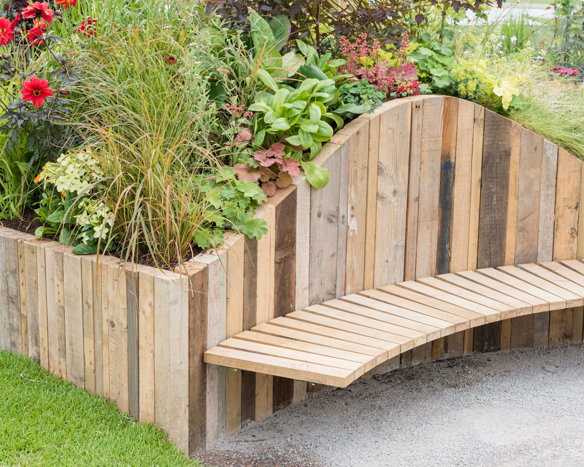 sloping raised bed with planting and wooden bench