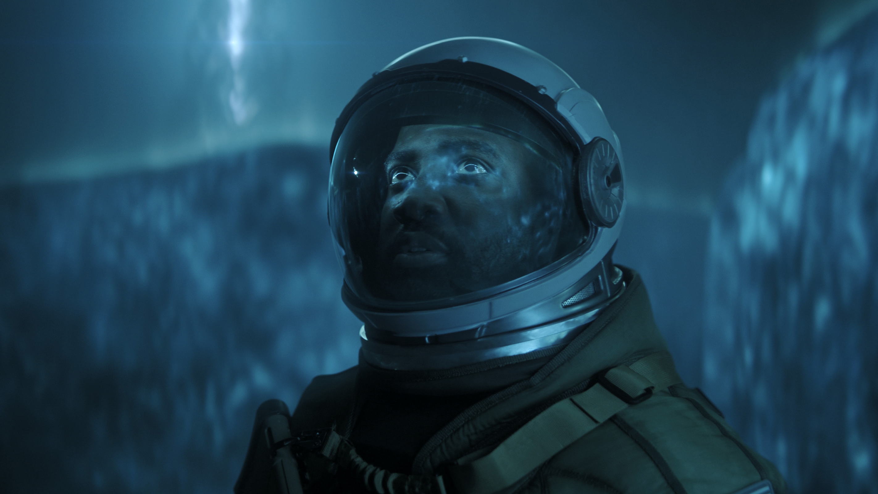 Trevante Cole wearing an astronaut suit looking up at something.