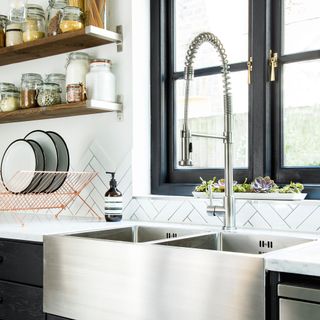 modern black kitchen with white tiles and surfaces and stainless steel sink
