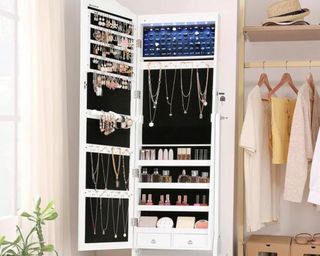 White open jewelry armoire from House of Hampton on Wayfair pictured next to open clothes rail with linen tops hanging