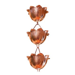 A copper rain chain with three lotus flower shaped holders hanging from it