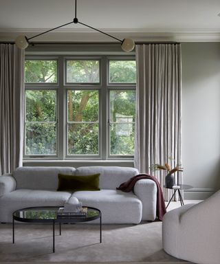 neutral living room with gray walls, modern minimal furniture and large window with neutral curtains