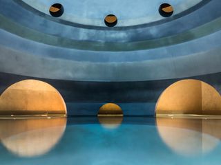 A utopian architecture-inspired spa features multiple concentric design features and a blue and sunset gold palette.