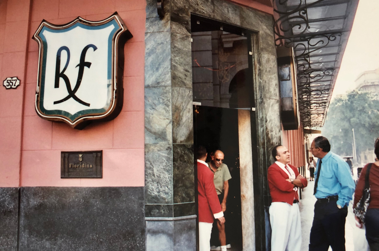 Bartenders and customers chat on a street corner outside a bar in Cuba