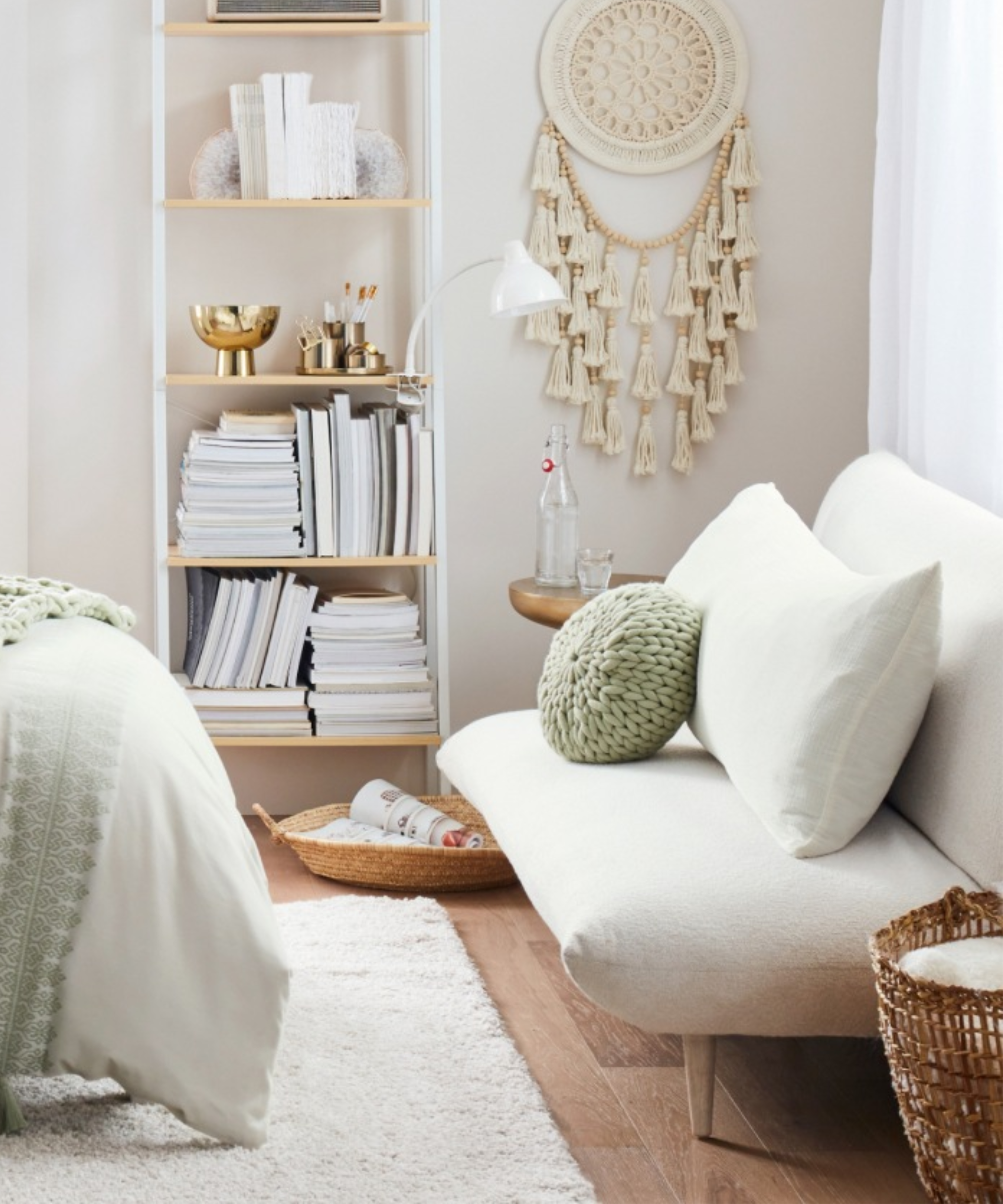 a bedroom with a small couch, a bookshelf, and a macrame tapestry