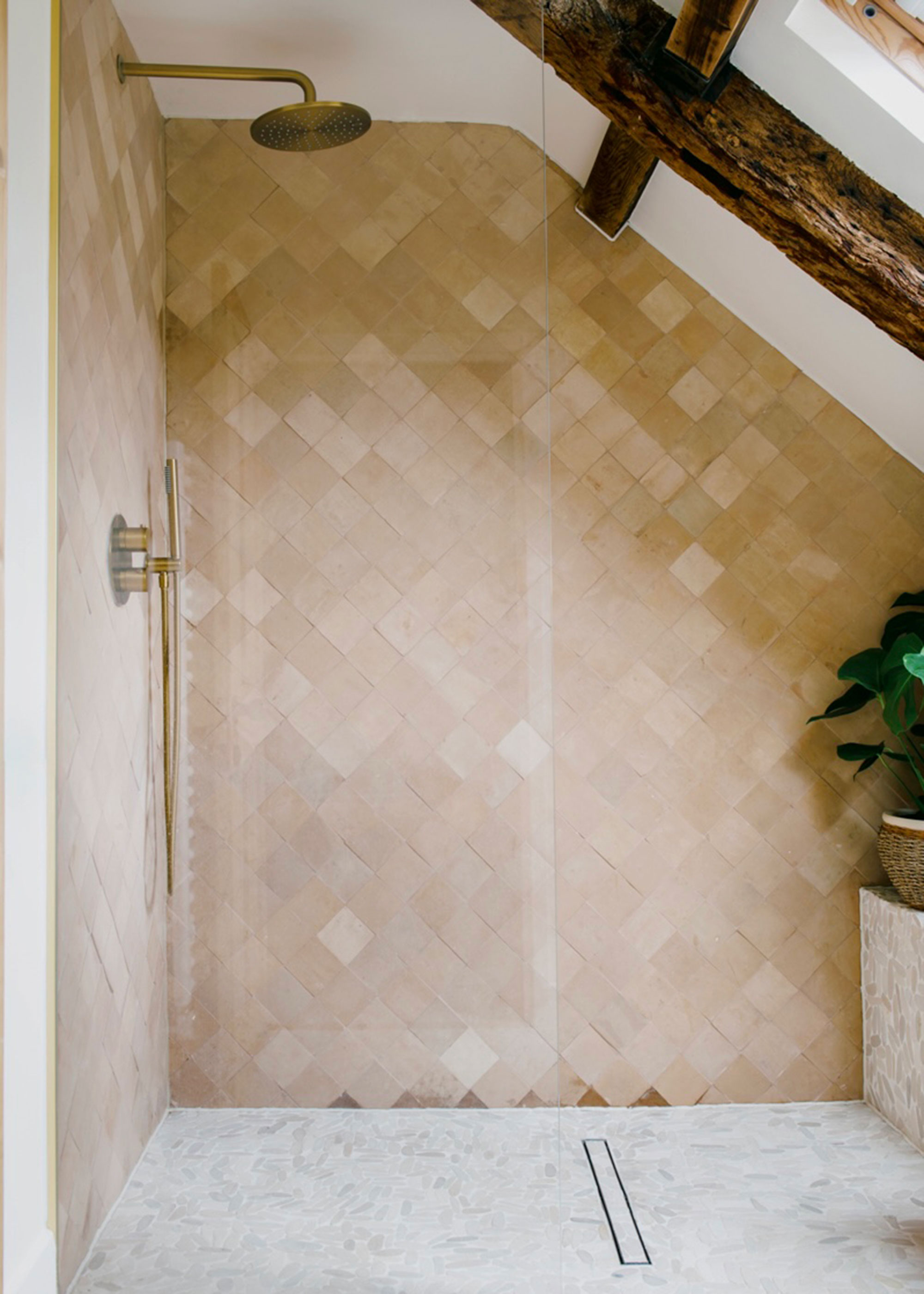 walk-in shower enclosure with stone tiles and brass fixed shower head