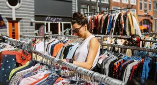 Woman looking through racks of secondhand clothing