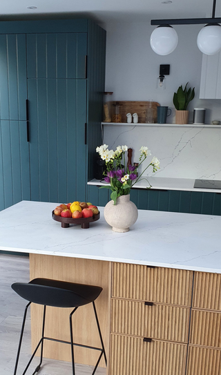 Ikea kitchen with base and wall cabinets painted in Inchyra blue by Farrow & Ball and an island clad in oak