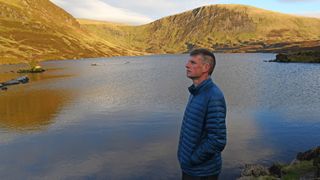 Hiker wearing Kathmandu Heli R Down Jacket at Loch Skeen