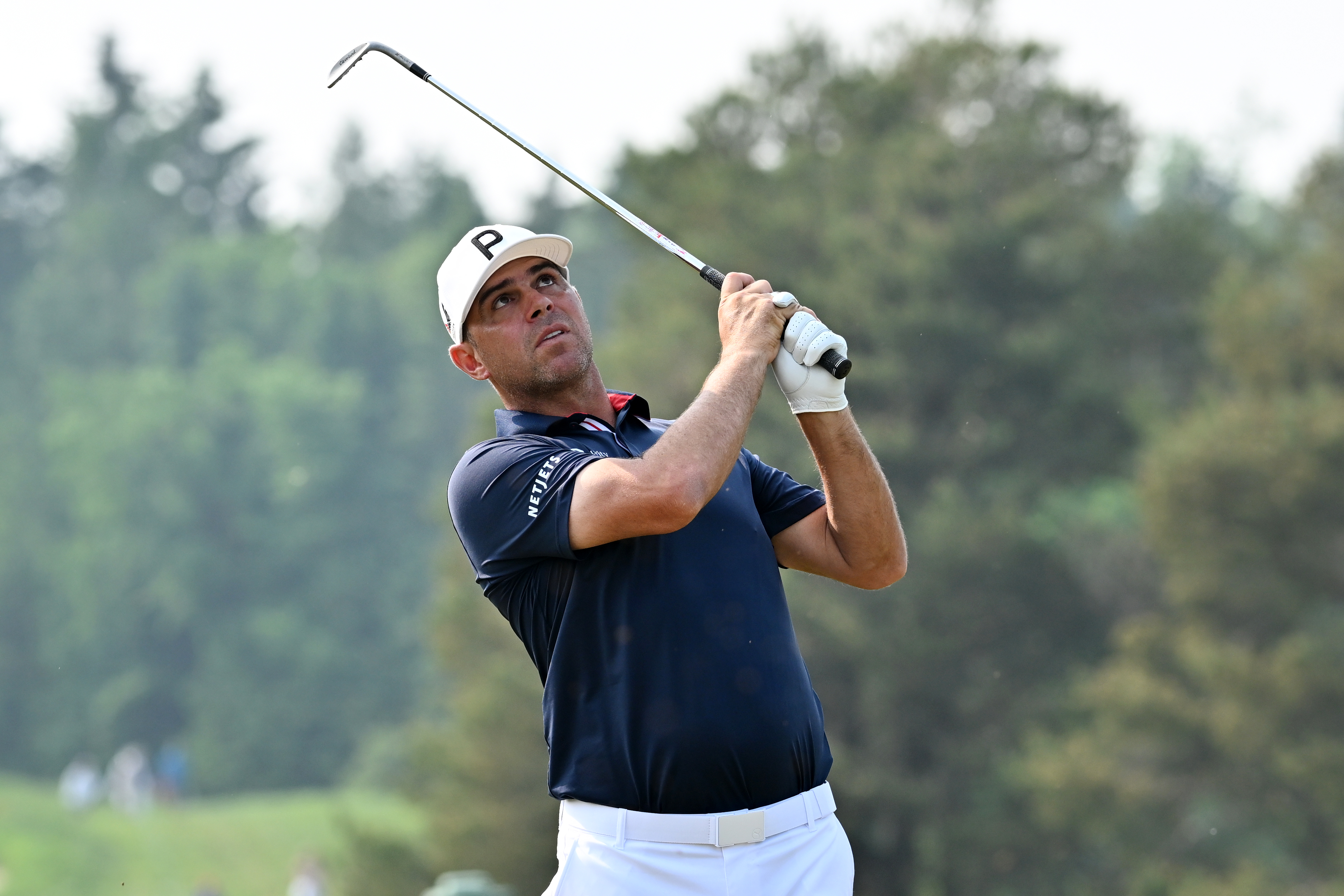 Gary Woodland strikes a wedge shot from the thick rough