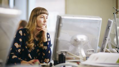 A small-business owner looks serious as she works on her computer at her desk. 