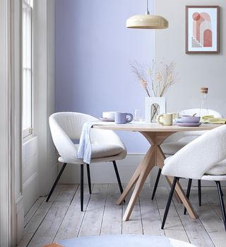 Pastel coloured mugs, bowls and plates on a light table surrounded by chairs