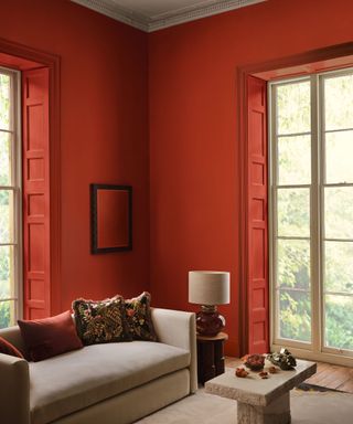 living room with large windows, bright red walls, neutral sofa