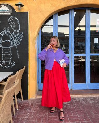 @oliviamarcus wears a red skirt and purple cardigan