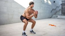 topless man performing bodyweight squat