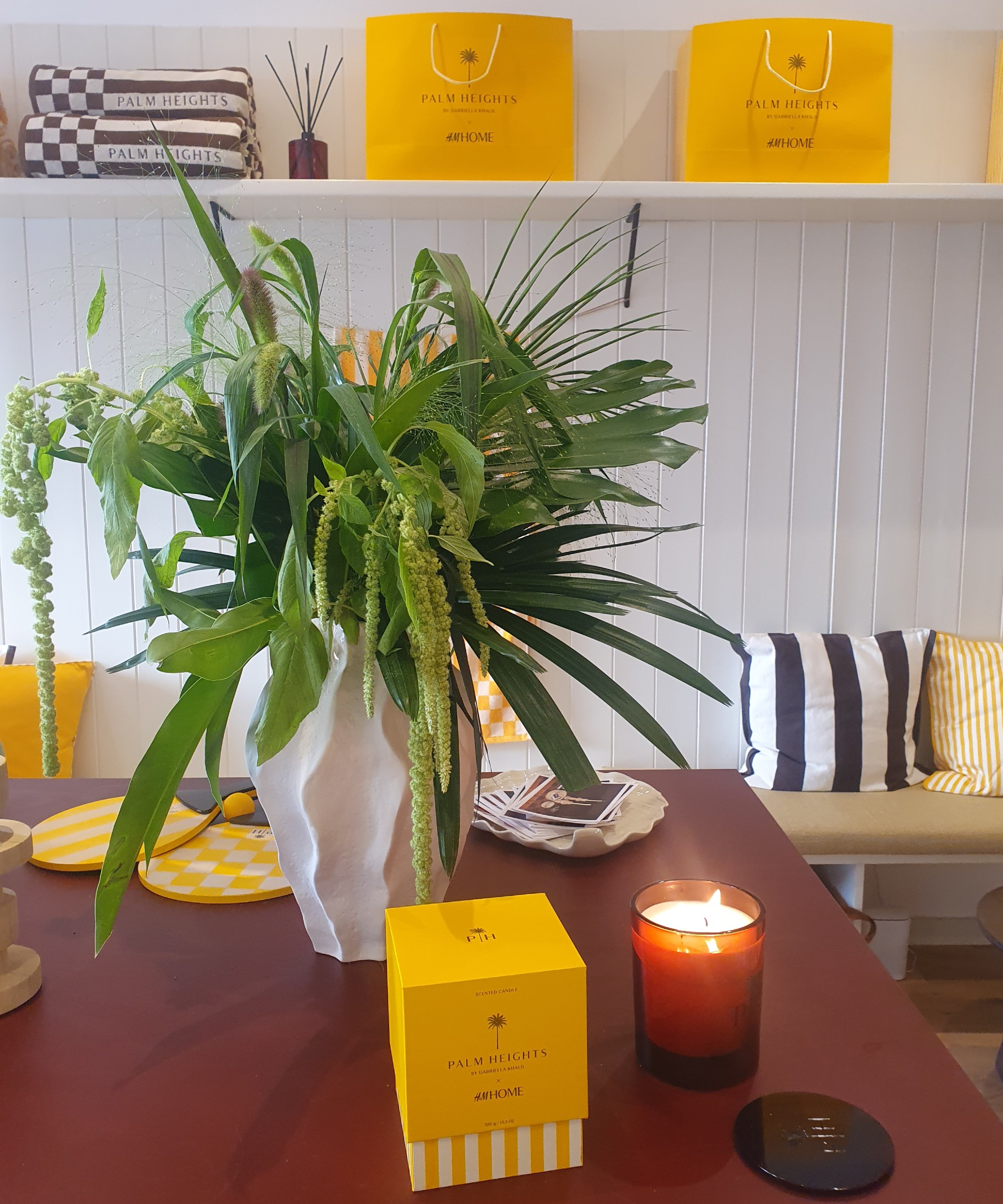 Scented candle from the H&M Home x Palm Heights collaboration next to a flower arrangement at the press preview of the range