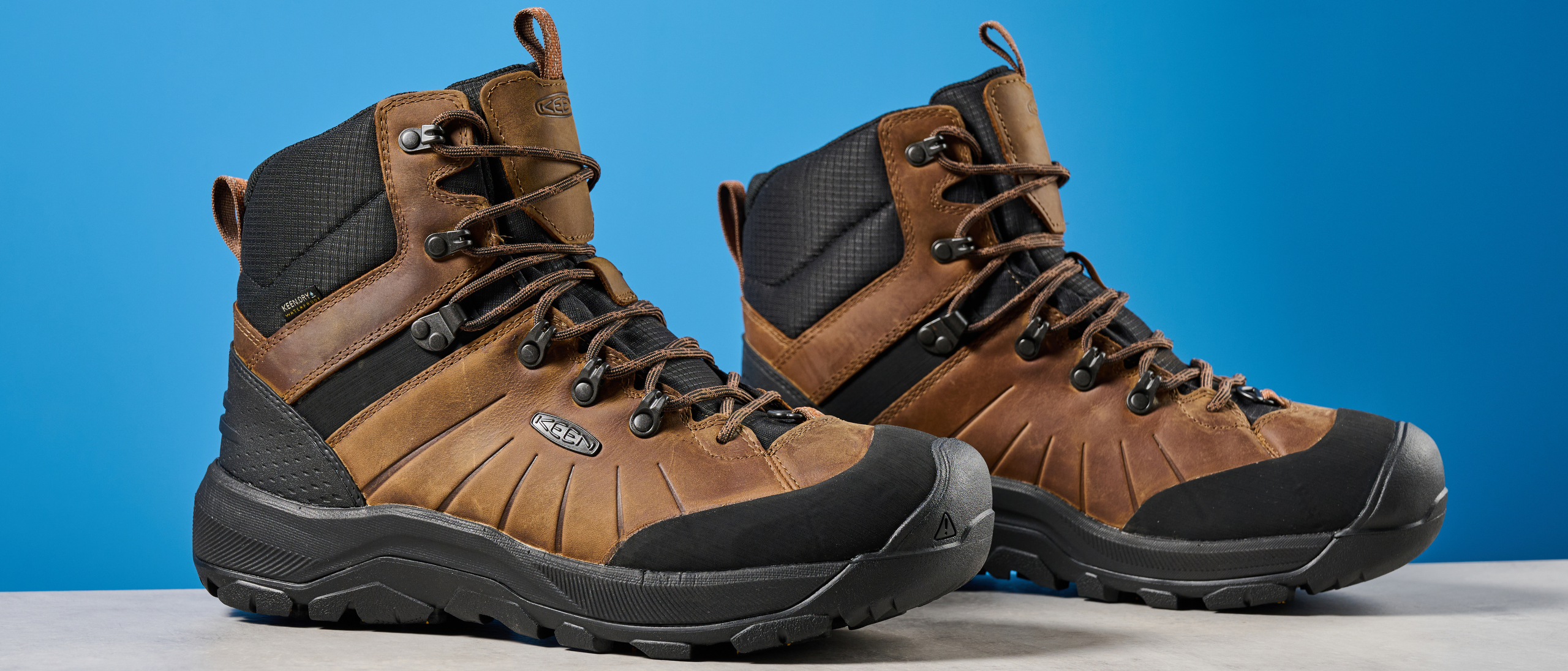 The Keen Revel IV in brown on a stone surface with a blue background