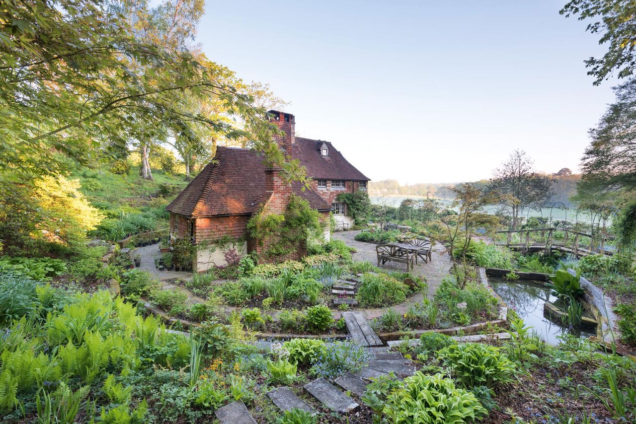 The garden of Copyhold Hollow, mere lawns when Frances Druce arrived more than 25 years ago, surrounds the 16th-century house, with waterways, a bridge, terrace and stepped beds. Copyhold Hollow, West Sussex. Photography by Mimi Connolly.