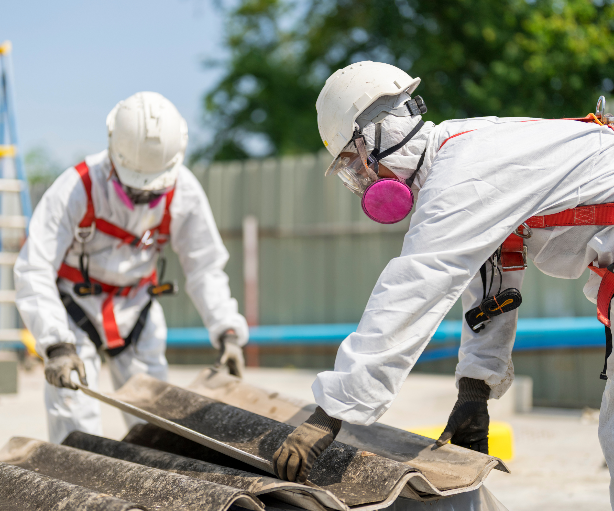 Two people wearing PPE holding roof tiles