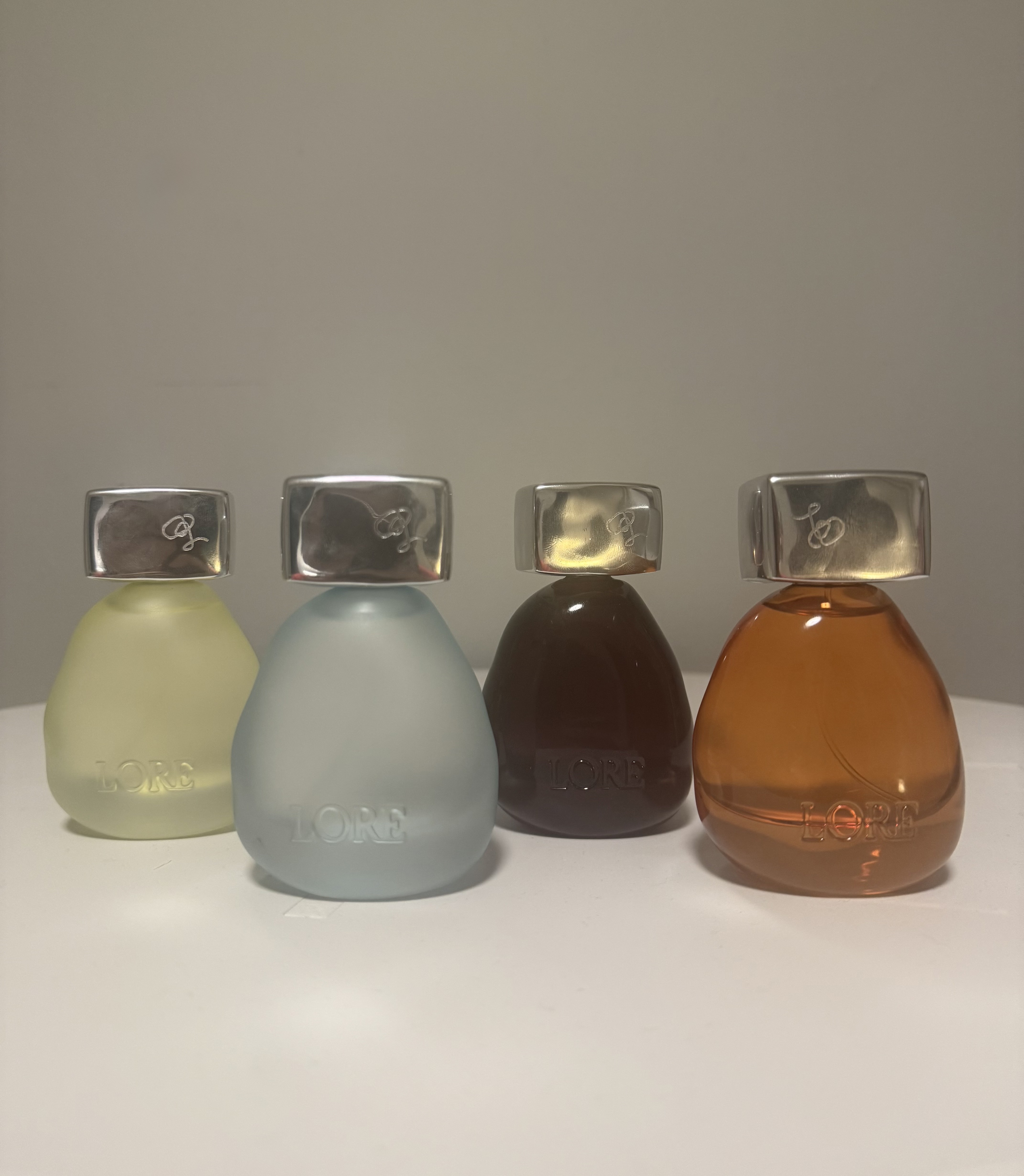 Lore fragrance bottles on white stand against grey wall