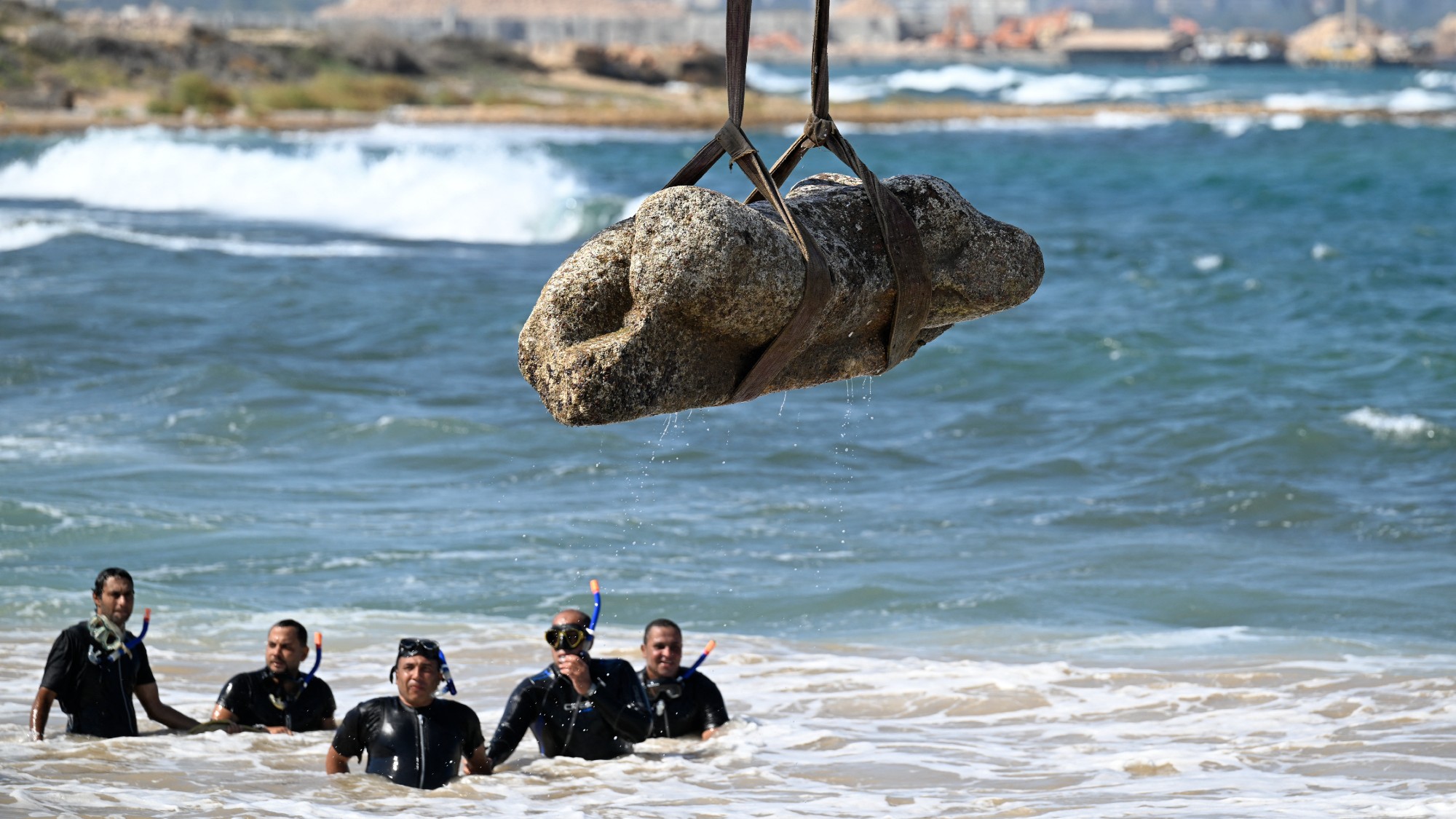 Divers look on as a crane lifts an artefact from the waters of Abu Qir Bay in the Egyptian port city of Alexandria