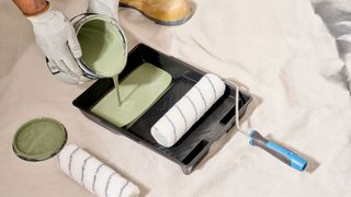 rollers and tray on floor with paint being poured into tray