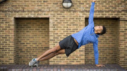 Man holding a side plank outside