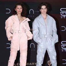 Zendaya and Timothee Chalamet wearing matching leather jumpsuits in pink and blue respectively