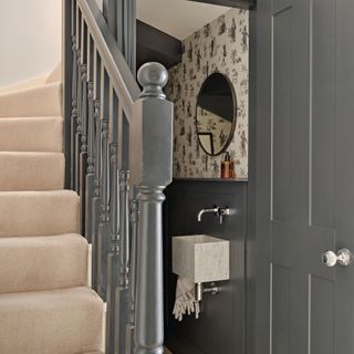 Hallway with charcoal grey staircase and door into downstairs toilet.