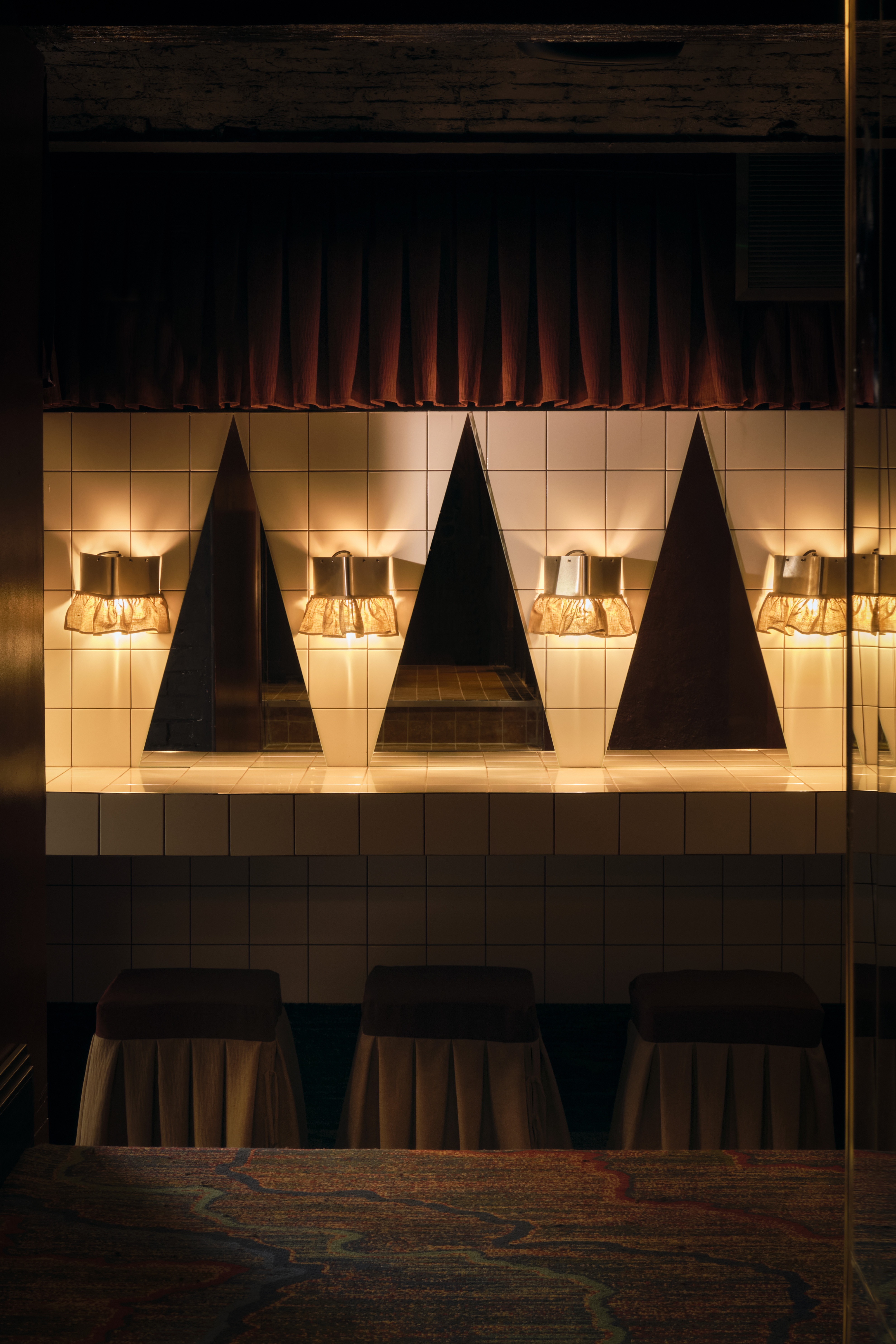 A golden-hued, dimly lit nightclub features velvety red or ochre plush fabrics, reflective surfaces, Art Deco-inspired sconces, and an air of mystery.