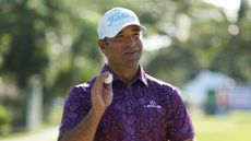 Rafael Campos holds his ball up to the crowd while wearing a purple golf shirt with poker icons all over