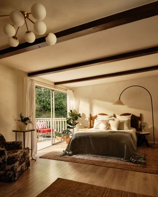 A bedroom with wooden beams, wooden flooring, and a balcony