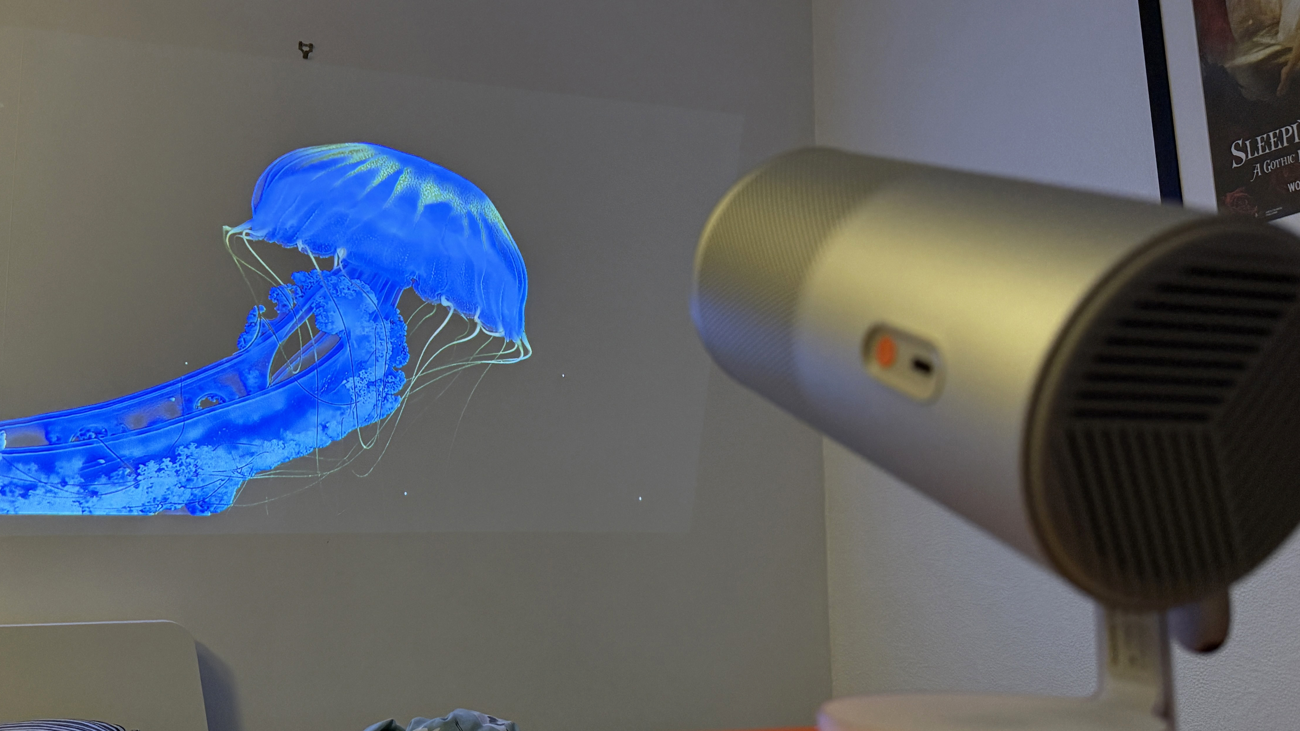 The XGIMI MoGo 4 portable projector showing an image of a jellyfish, on a black background, but the background has faded into the wall