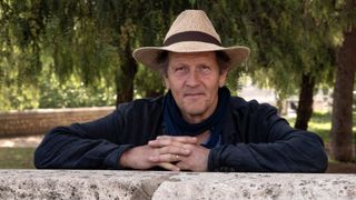 Monty Don in a straw hat leans on a wall in Monty Don's Spanish Gardens